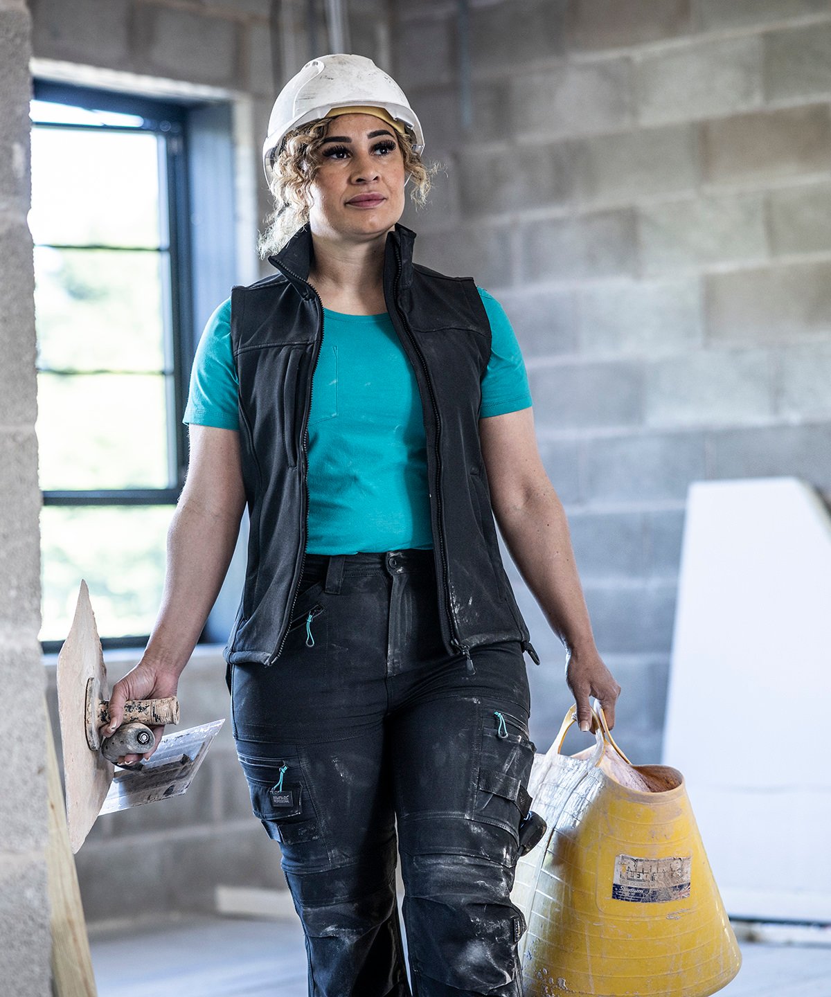 Female model wearing the RG155 Flux gilet in a professional outdoor setting, demonstrating the athletic fit and weather resistance.