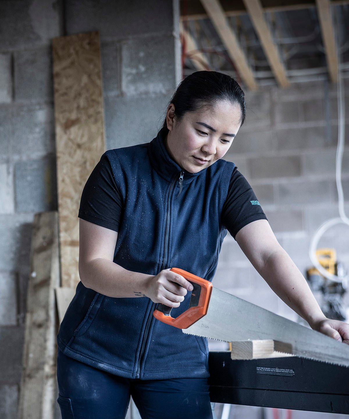 Women’s professional workwear gilet being worn in a workshop setting; showing the durable microfleece fabric and practical zipped pockets for tools.